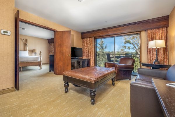 Hotel suite with a bed, living room, and a view outside through sliding glass doors.