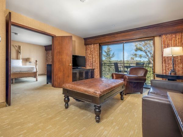Hotel suite with a bed, living room, and a view outside through sliding glass doors.