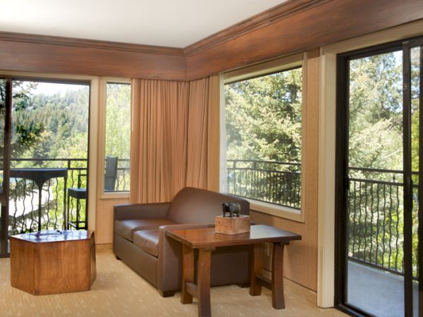 Cozy room with sofa, table, and balcony overlooking trees.