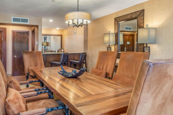 A dining room with a long wooden table, leather chairs, and a chandelier.