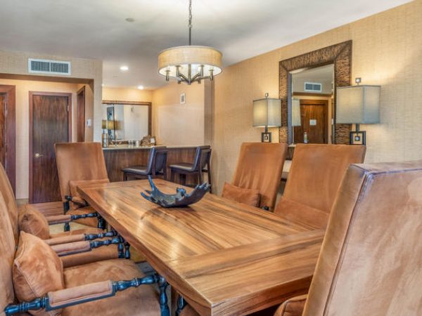 A dining room with a long wooden table, leather chairs, and a chandelier.