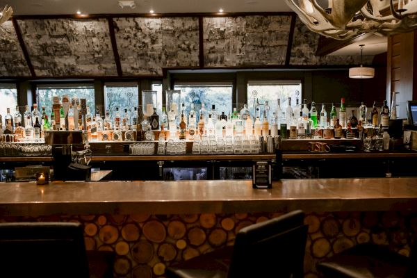 A well-stocked bar with various bottles, a counter, and bar stools.