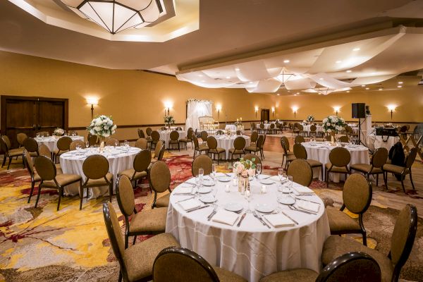 Elegant banquet hall with set tables, floral centerpieces and sophisticated decor.