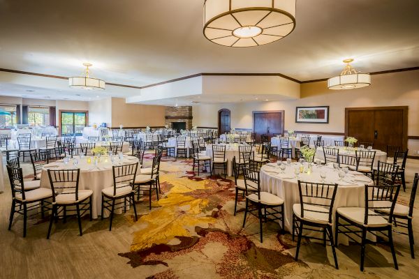 Elegant dining hall set up with round tables, white tablecloths, and fancy settings.