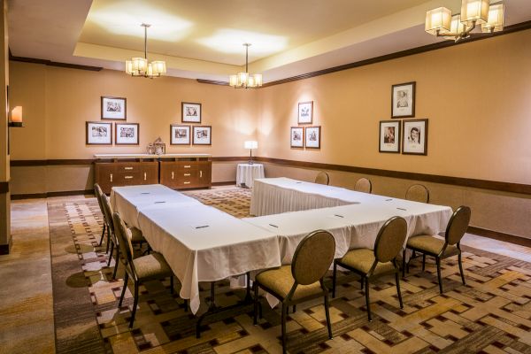 Conference room with a long table, chairs, framed pictures on walls, and overhead lighting.
