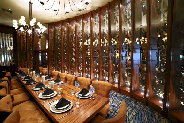 Elegant dining room with a long table, plush chairs, and decorative wine racks.