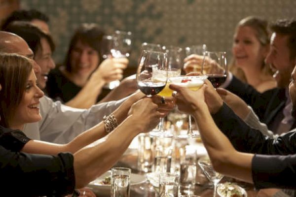 Group of people toasting with wine glasses at a dinner table, celebrating.