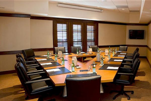 A well-lit boardroom with a large table, chairs, and notepads for a meeting.