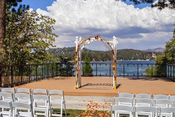 Outdoor wedding setup with chairs, a decorated arch, and a lake view.