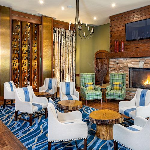 Cozy room with fireplace, wine storage wall, plush chairs, wood accents, and striped carpet.