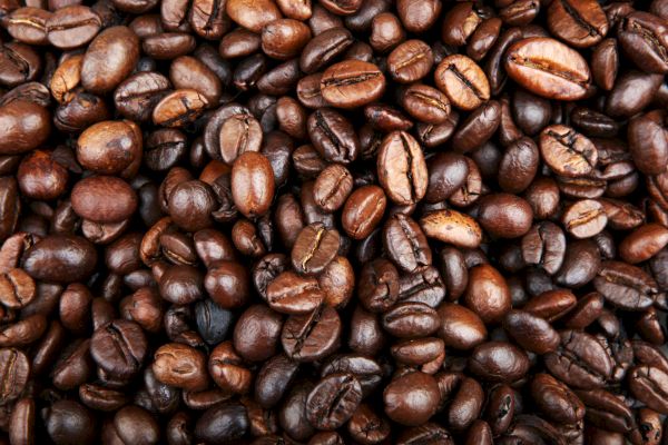 The image shows a close-up of numerous roasted coffee beans.