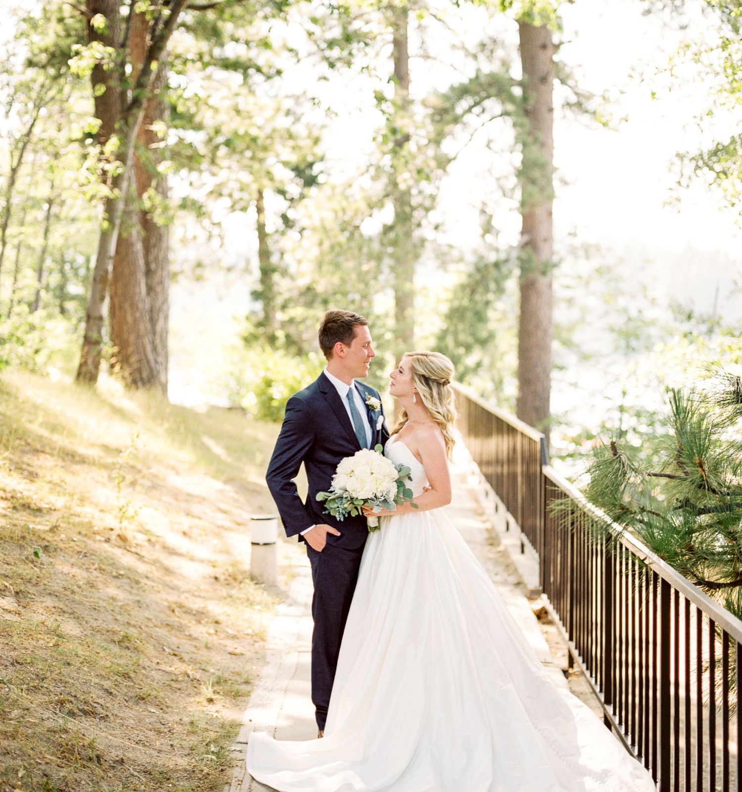 A bride and groom are standing together outdoors, likely on their wedding day.