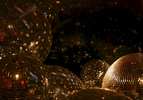 The image shows several disco balls reflecting light in a dark setting, creating a sparkling and festive atmosphere.
