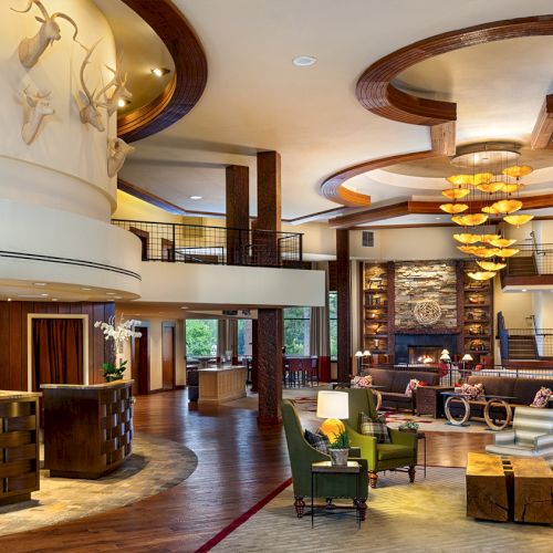 The image shows a luxurious hotel lobby with a reception desk, elegant décor, seating areas, and wooden accents throughout the space.