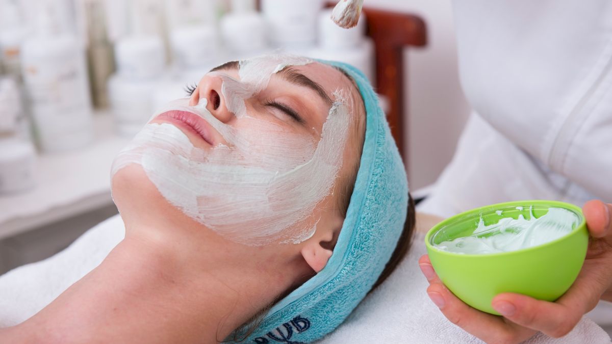 A person is receiving a facial treatment, while a mask is being applied to their face with a brush.